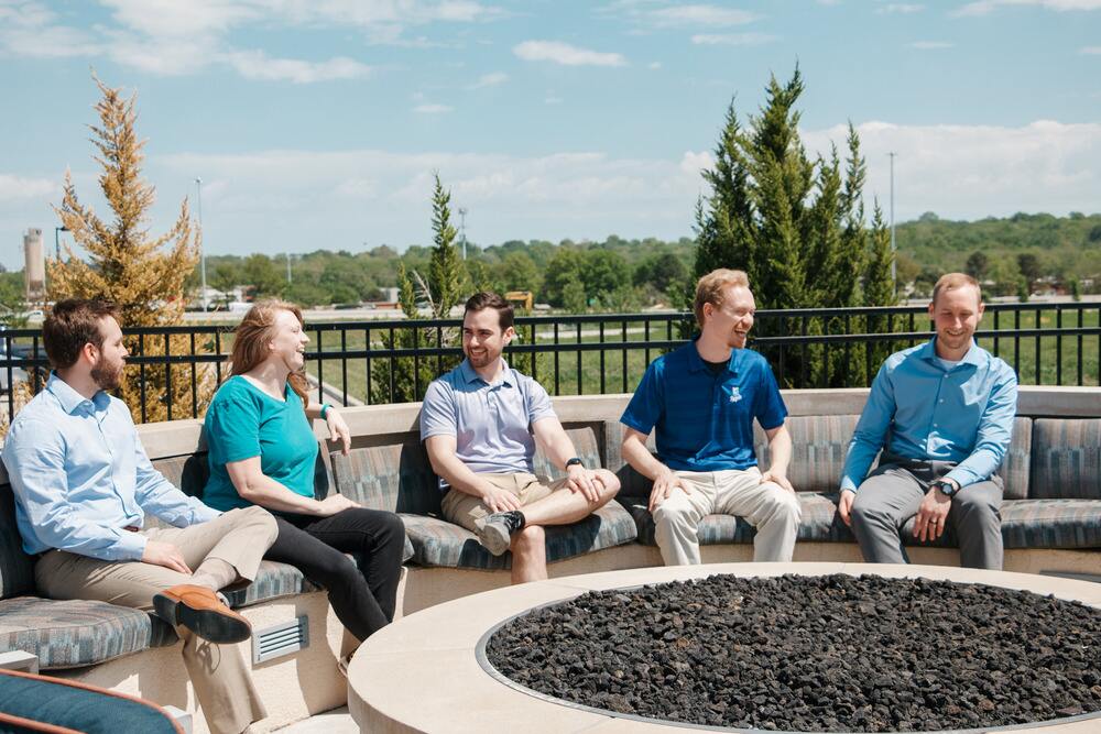 ARC 4 men 1 woman laughing next to fire pit