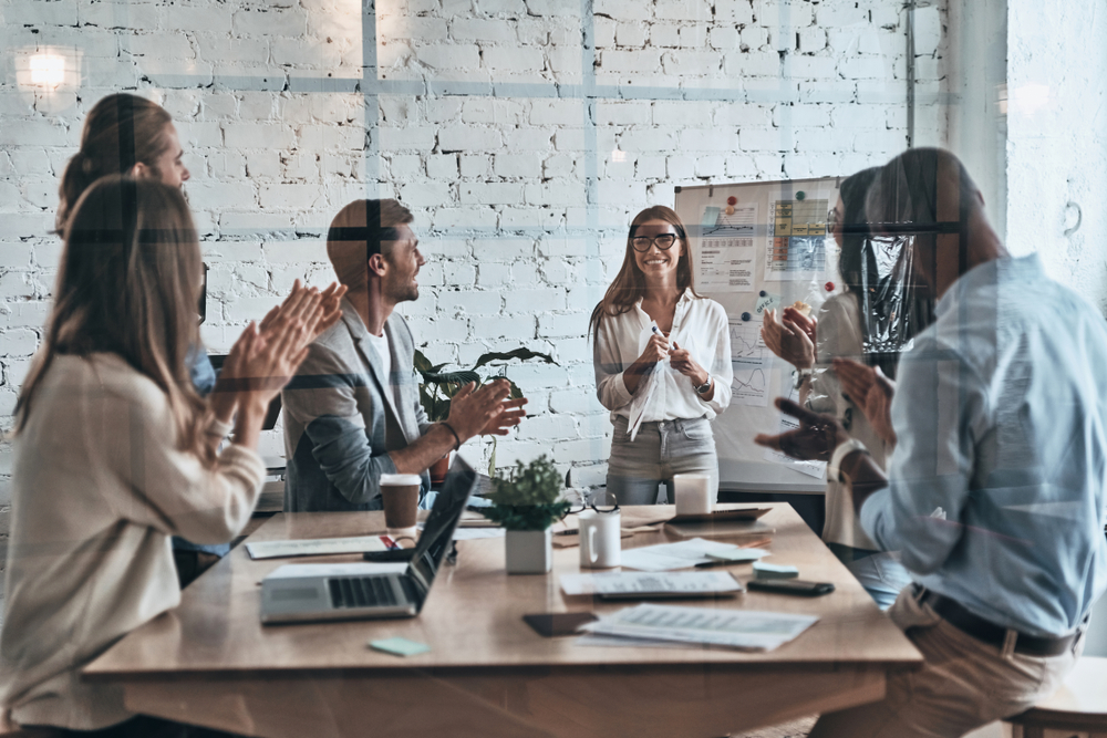 Group of people in a conference room dressed professionally, having a conversation.