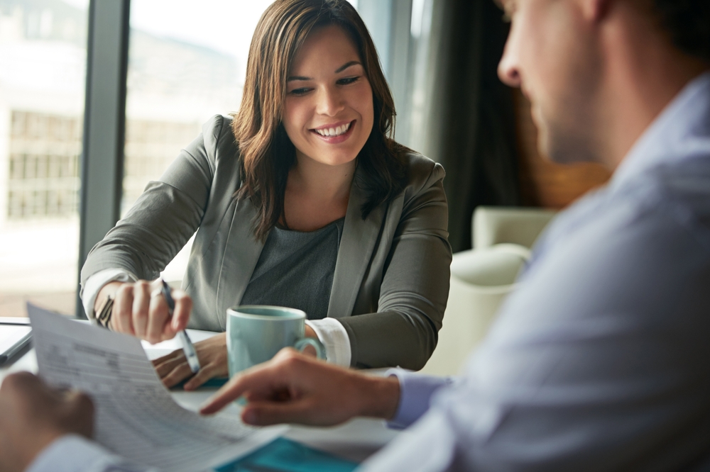 Business professionals sitting at a table looking at papers, happy.