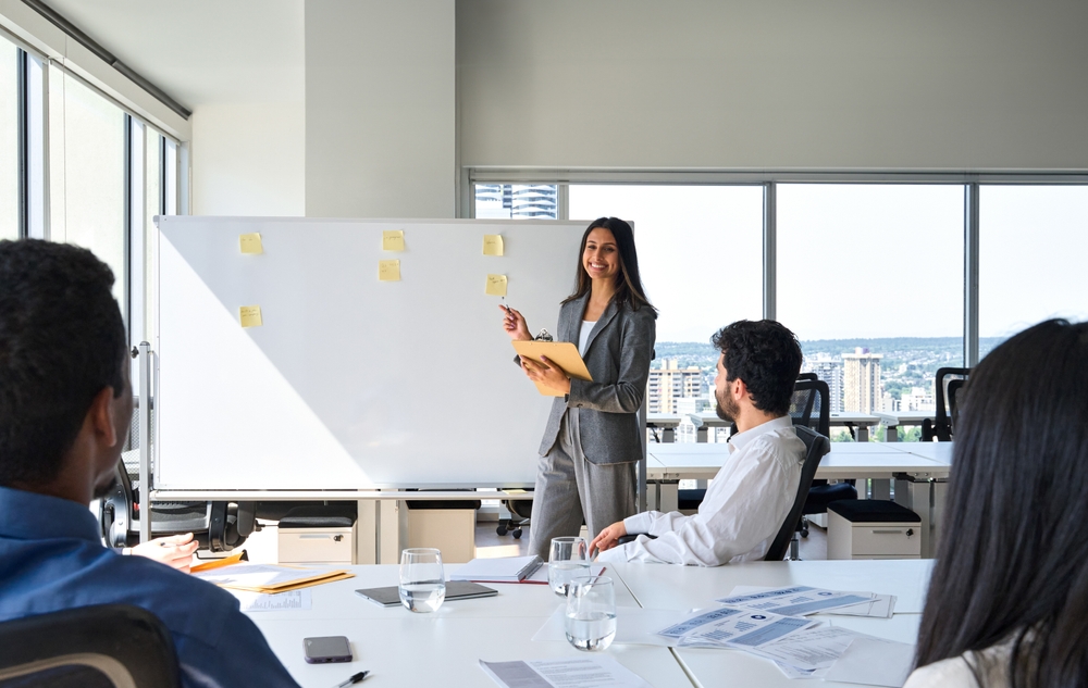 Image of professionals in a room looking at a large white board with nothing on it