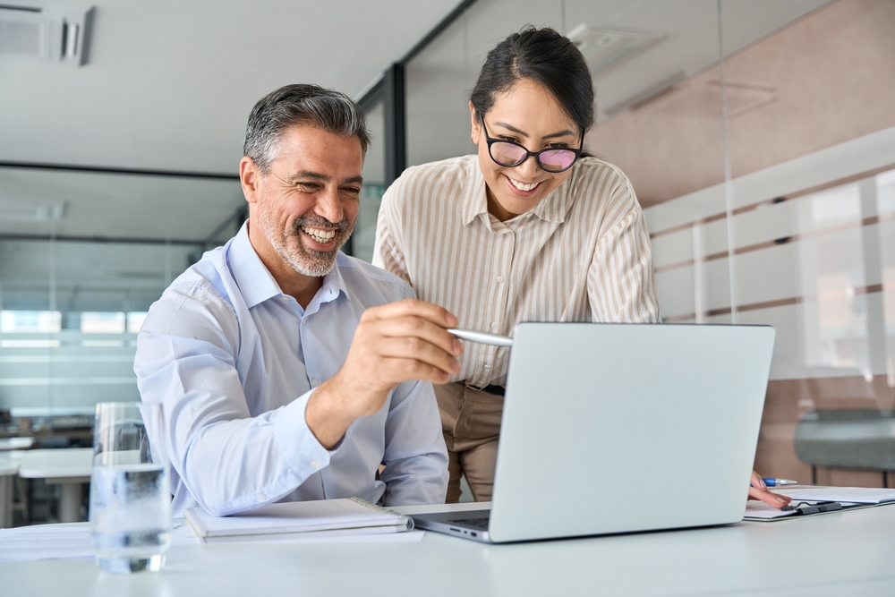 Business professionals looking at a laptop and smiling