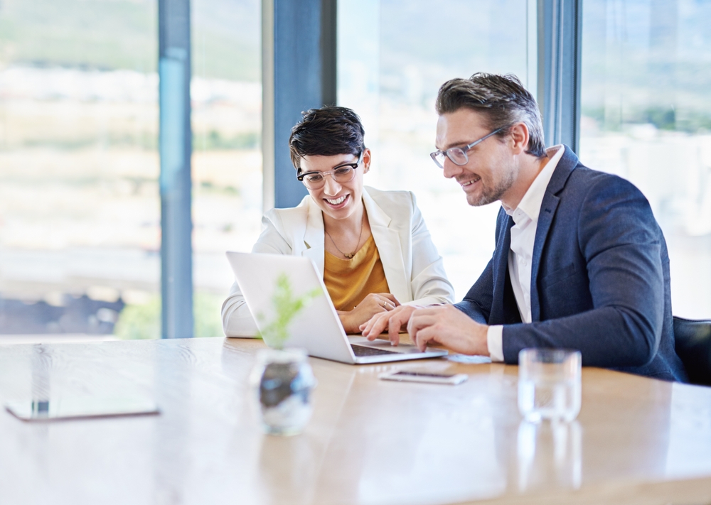 business professionals looking at a laptop and smiling.